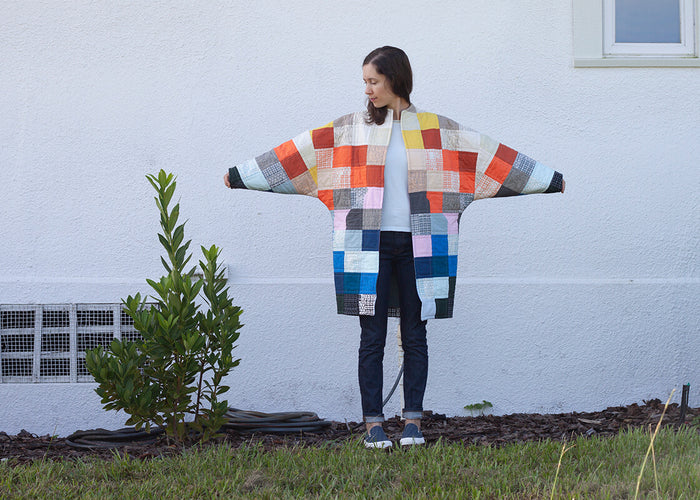 colorful quilted coat being worn with arms extended showing the overall shape