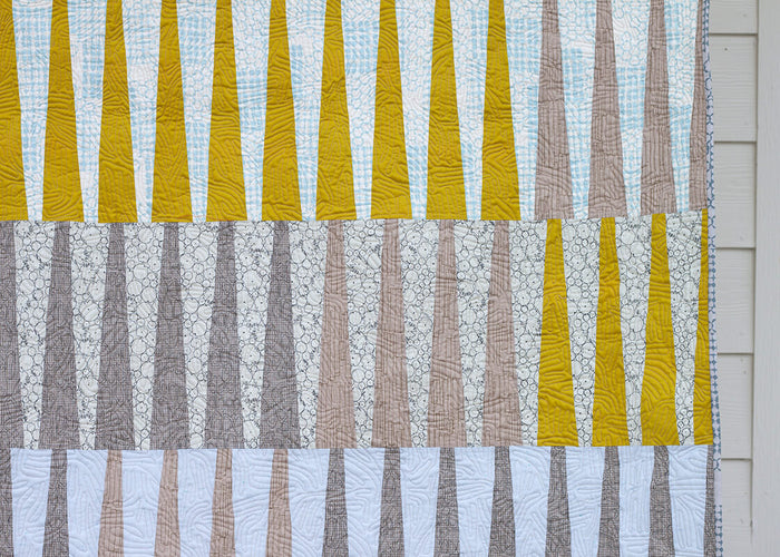 close up of yellow, grey and blue fabrics in a pieced quilt